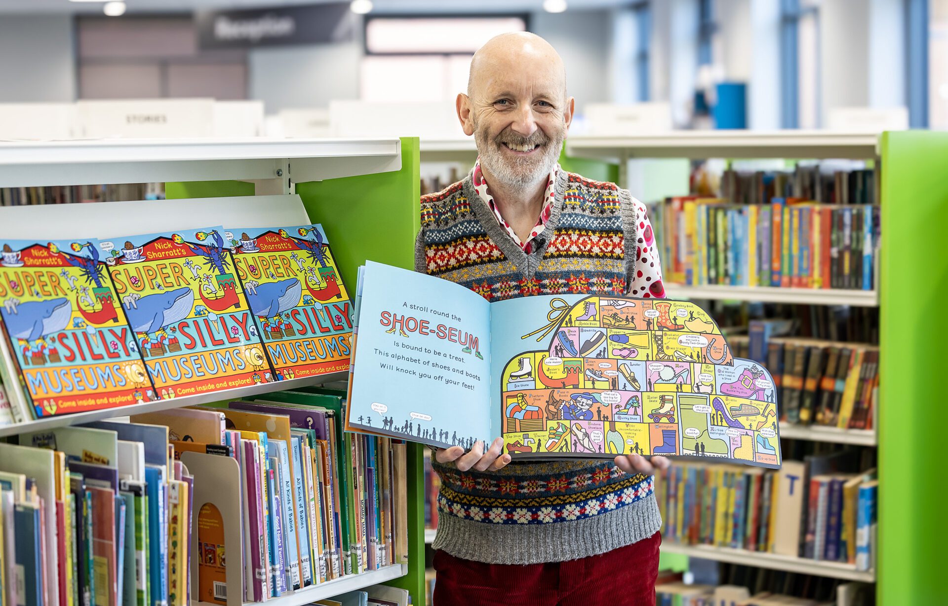 Image of a man holding up a book inside a library